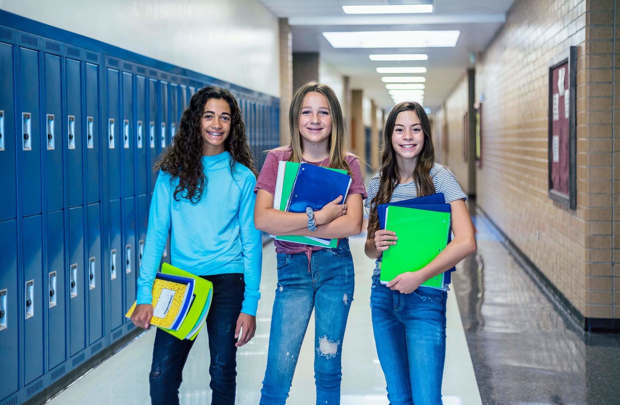 Students walking down a school hallway with notebooks